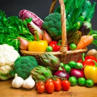 Raw vegetables in wicker basket on wooden table